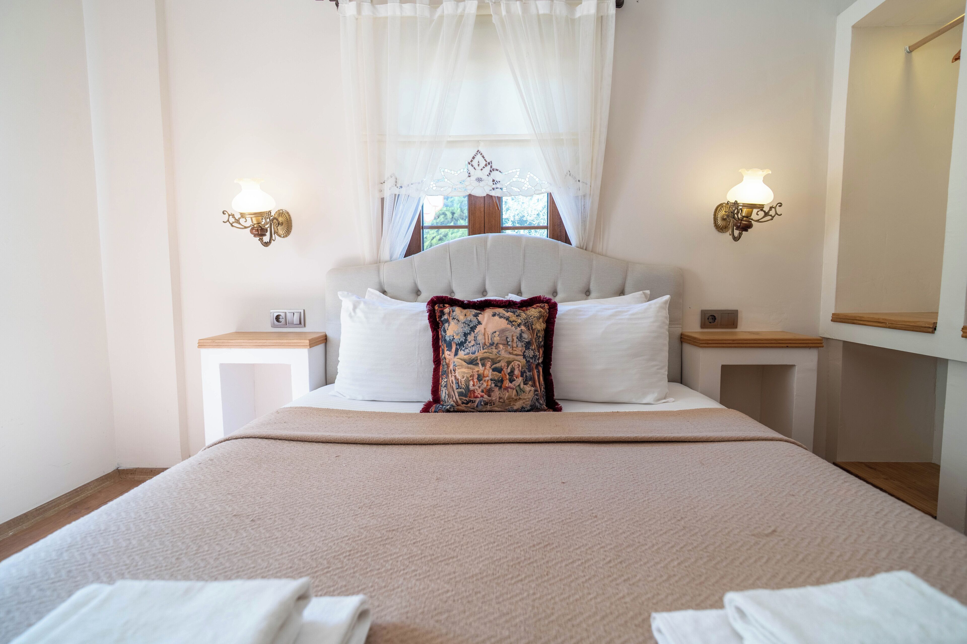 A neatly made bed with a decorative pillow, two bedside tables with lamps, and a large mirror on the wall.