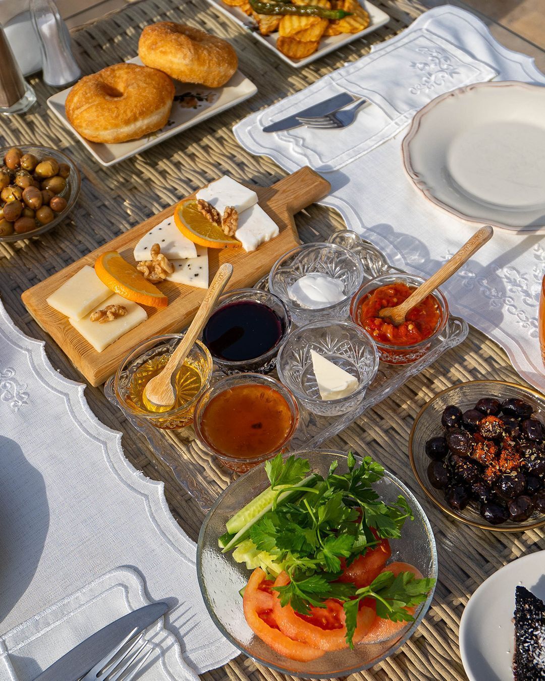 Una mesa dispuesta con diversos alimentos, entre ellos queso, nueces, aceitunas y una ensalada, indicando una preparación para comer.