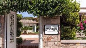 A stone wall with a sign for 'VRODI otel' and a gate with decorative ironwork. - Cunda Vrodi By House (Ayvalik)