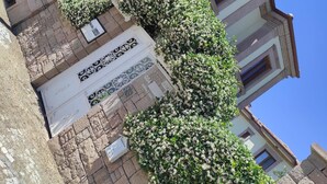 A multi-story building with a balcony, a small garden, and a sign with the text "VROdilote". - Cunda Vrodi By House (Ayvalik)