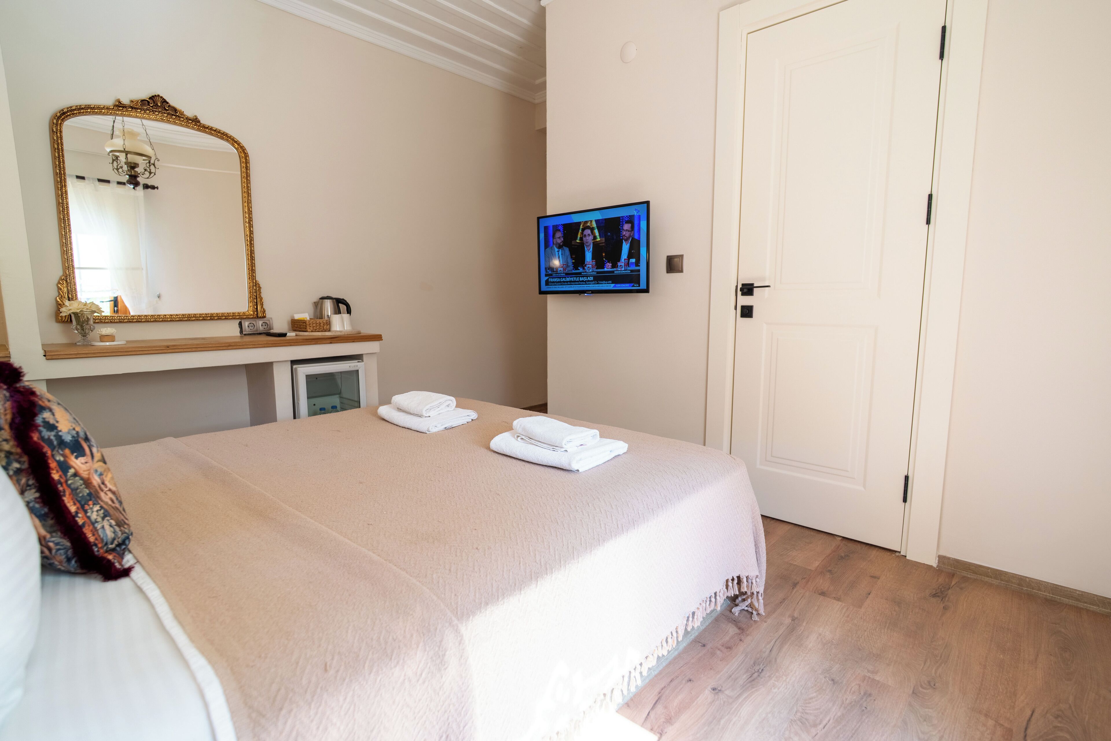 Ein Hotelzimmer mit Bett, Fernseher, Spiegel und Tür.