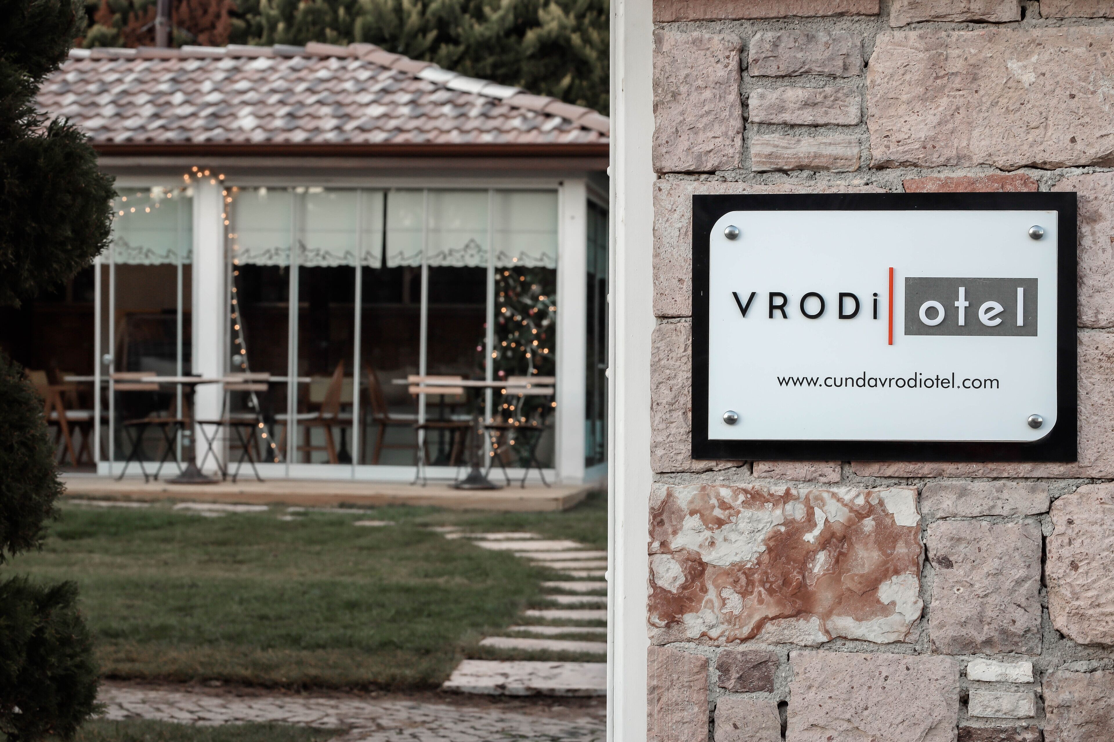 A sign for 'VRODI Hotel' with a website URL.