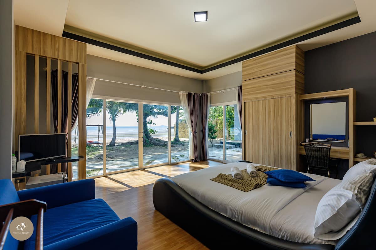 A bedroom with a bed, a TV, and a view of the beach.