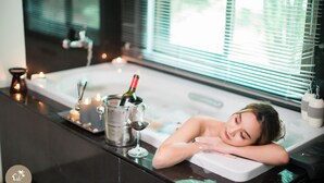 A bathtub with a bottle of wine and a glass, candles, and a window with blinds. - Pak Nam Resort (La-ngu)