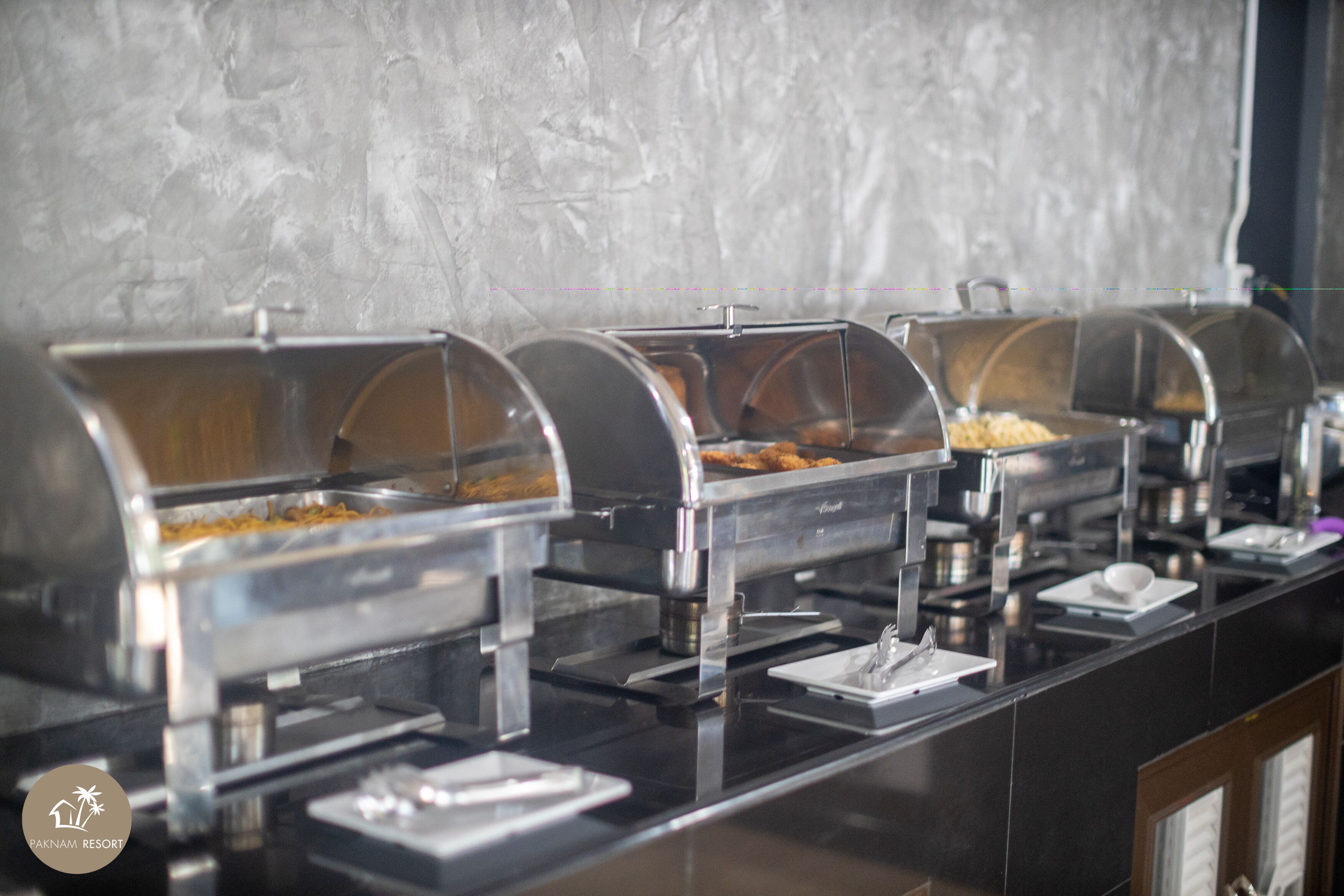 A buffet setup with multiple self-service food stations, each with a covered serving area and utensils provided.