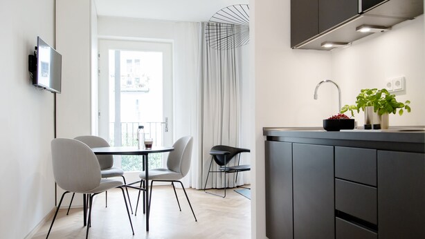 Una cocina moderna con comedor, que incluye un televisor de pantalla plana, una mesa de comedor con sillas y una isla de cocina con pileta y planta en maceta.