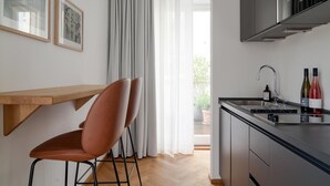 Una cocina moderna con una mesa de madera y dos sillas, un horno empotrado y un lavamanos con botellas de vino.