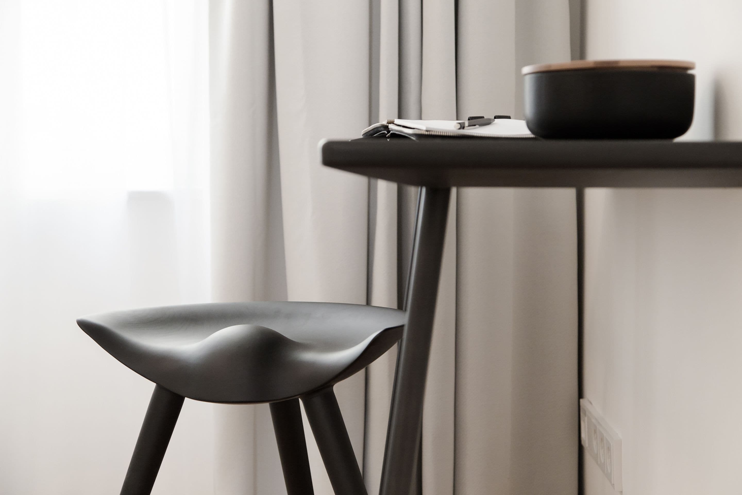 Una silla moderna y una mesita con un tazón y papeles.