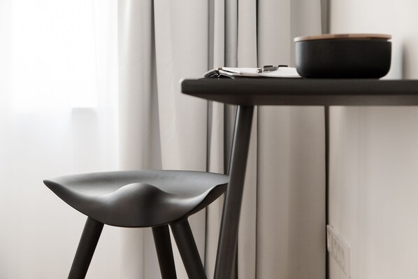Una silla moderna y una mesita con un tazón y papeles.