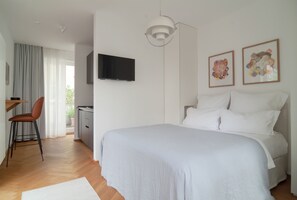 A modern bedroom with a large bed, a desk, and a chair.