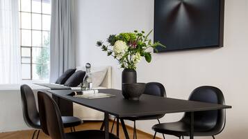Ein moderner Essbereich mit einem schwarzen Tisch, vier schwarzen Stühlen, einer Vase mit Blumen und minimalistischer Einrichtung.