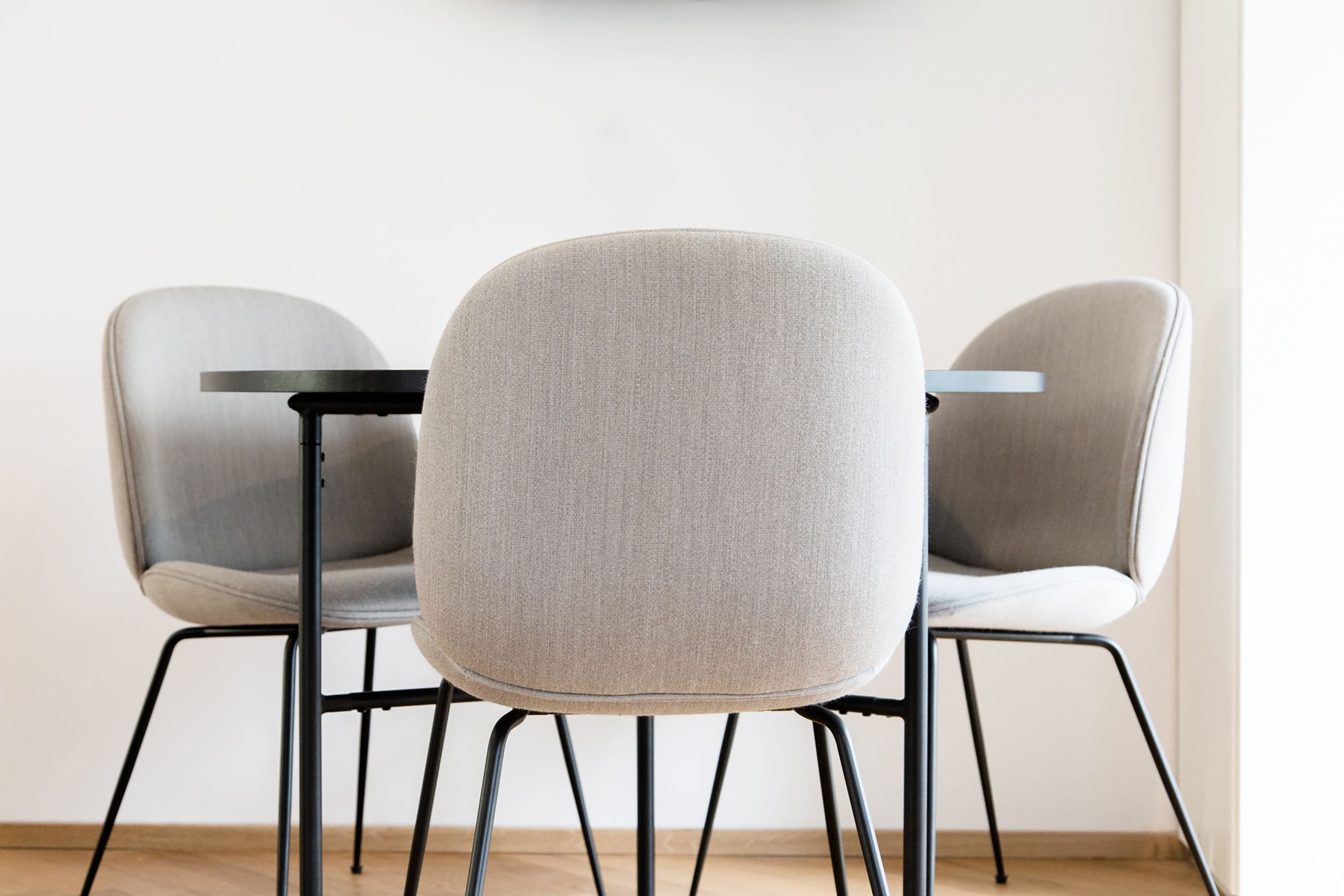 Three modern chairs with metal legs and a round table.