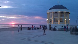 A coastal building with a dome, people walking around, and a sunset in the background. - Hotel Strandvilla Janine (Borkum)