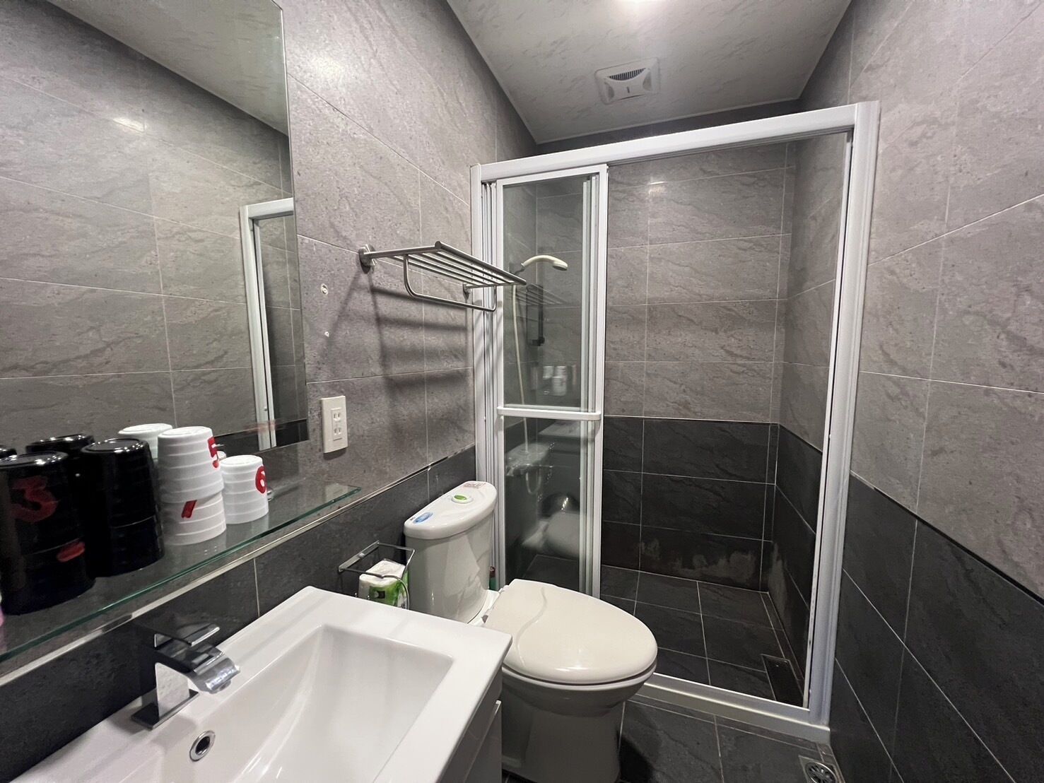 Une salle de bain moderne avec une douche à parois de verre, un lavabo blanc et des toilettes.