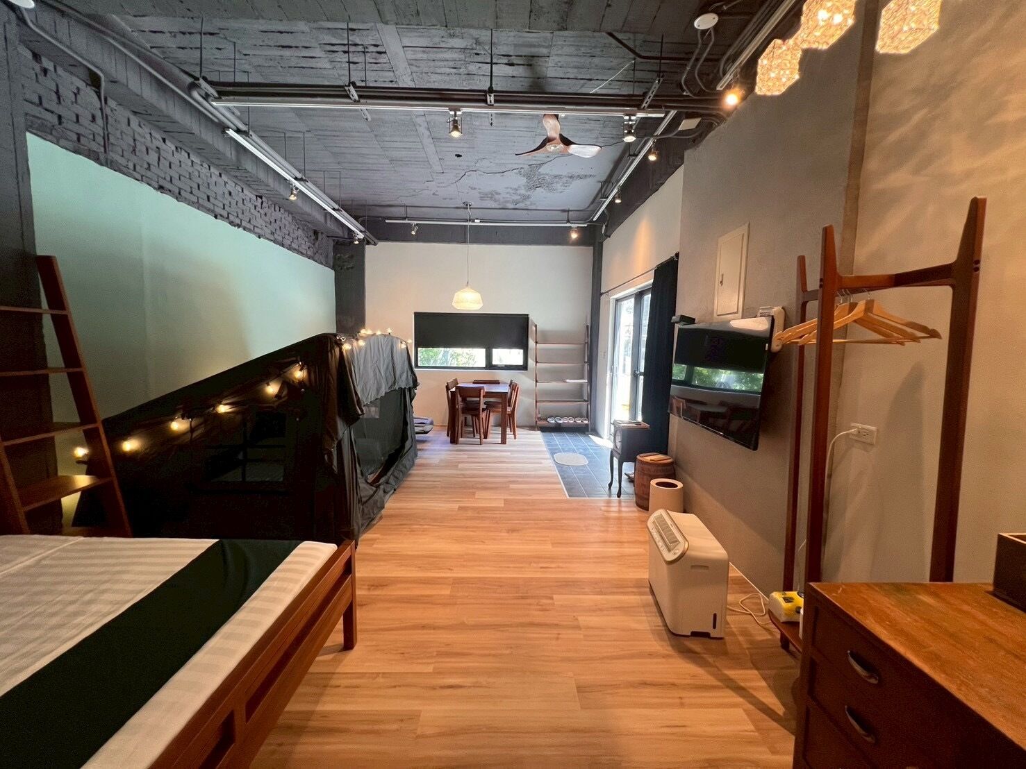 A modern hotel room with a bed, a desk, a TV, and a wardrobe.