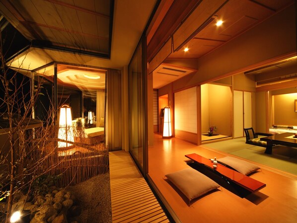 A modern interior with a wooden floor, a seating area with cushions, and a dining table.