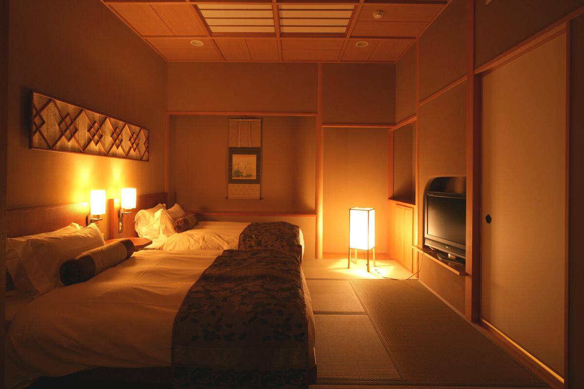 Ein Hotelzimmer mit Bett, Nachttischlampen, einem Fernseher und einem Bild an der Wand.