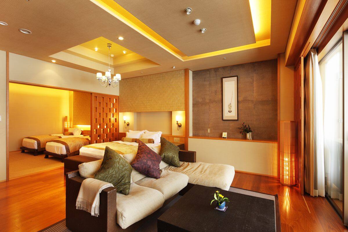 Ein modernes Hotelzimmer mit einer Sitzecke, einem Couchtisch und einem Bett mit vielen Kissen.