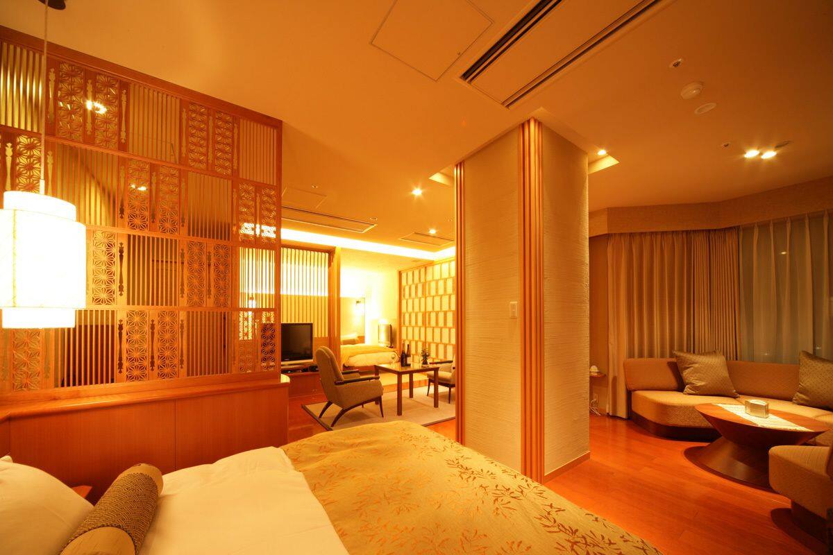 Ein Hotelzimmer mit Bett, Schreibtisch, Sofa und Fernseher.