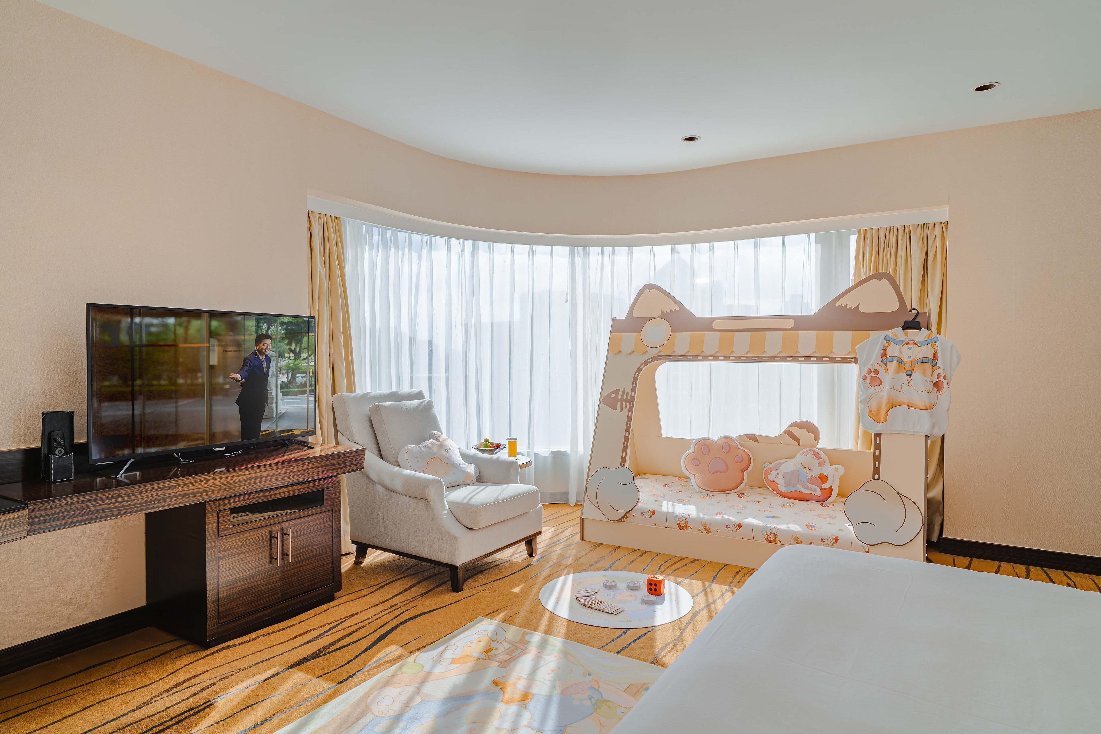 Hotelkamer met televisie, een sofa, een stapelbed en een kleine tafel met een drankje.