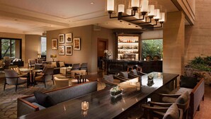 A spacious hotel lobby with a long dining table, comfortable seating, a bar area, and framed artwork on the walls. - The Kunlun Jing An (Shanghai)