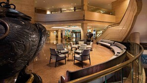 A spacious lobby with a curved seating area, a large decorative urn, and a staircase leading to an upper level. - The Kunlun Jing An (Shanghai)