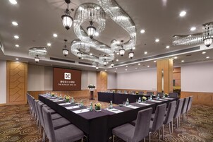 A conference room with a long table, chairs, and a screen displaying hotel information.