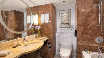 Un baño moderno con tocador de mármol, bañera independiente, inodoro y un espejo grande.