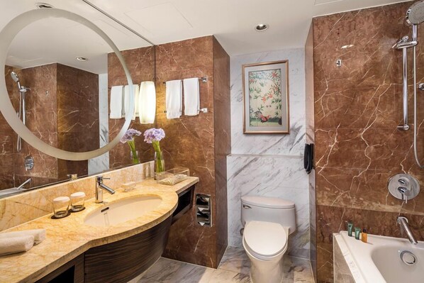 Un baño moderno con tocador de mármol, bañera independiente, inodoro y un espejo grande.