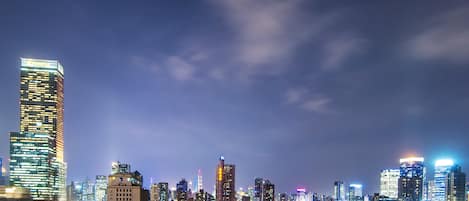 Un paisaje urbano nocturno con rascacielos iluminados y edificios residenciales.