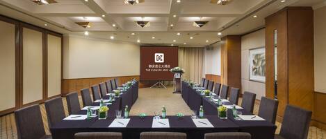 A conference room with a long table, chairs, and a podium with a banner.