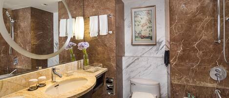 A modern bathroom with a freestanding bathtub, a large vanity with a curved sink, a toilet, and a shower area.