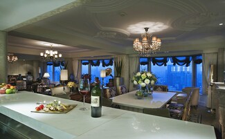 A spacious dining area with a marble bar, elegant chandeliers, and a city view.