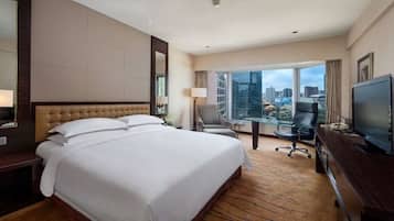 A hotel room with a large bed, a desk with a computer, a chair, and a TV.