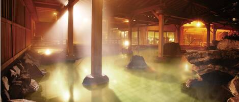 Um onsen japonês tradicional, com interior de madeira, assentos de pedra e chão de azulejos.