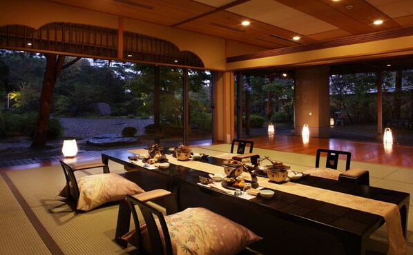 Une salle à manger de style japonais traditionnel, avec des tatamis, une table basse et une vue sur un jardin.