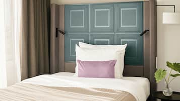 A hotel room with a bed, a nightstand, a lamp, and a window with curtains.