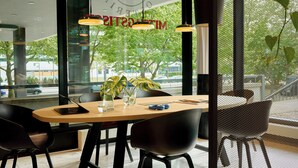 Un espace de salle à manger moderne avec une table en bois, des chaises noires et des luminaires suspendus.