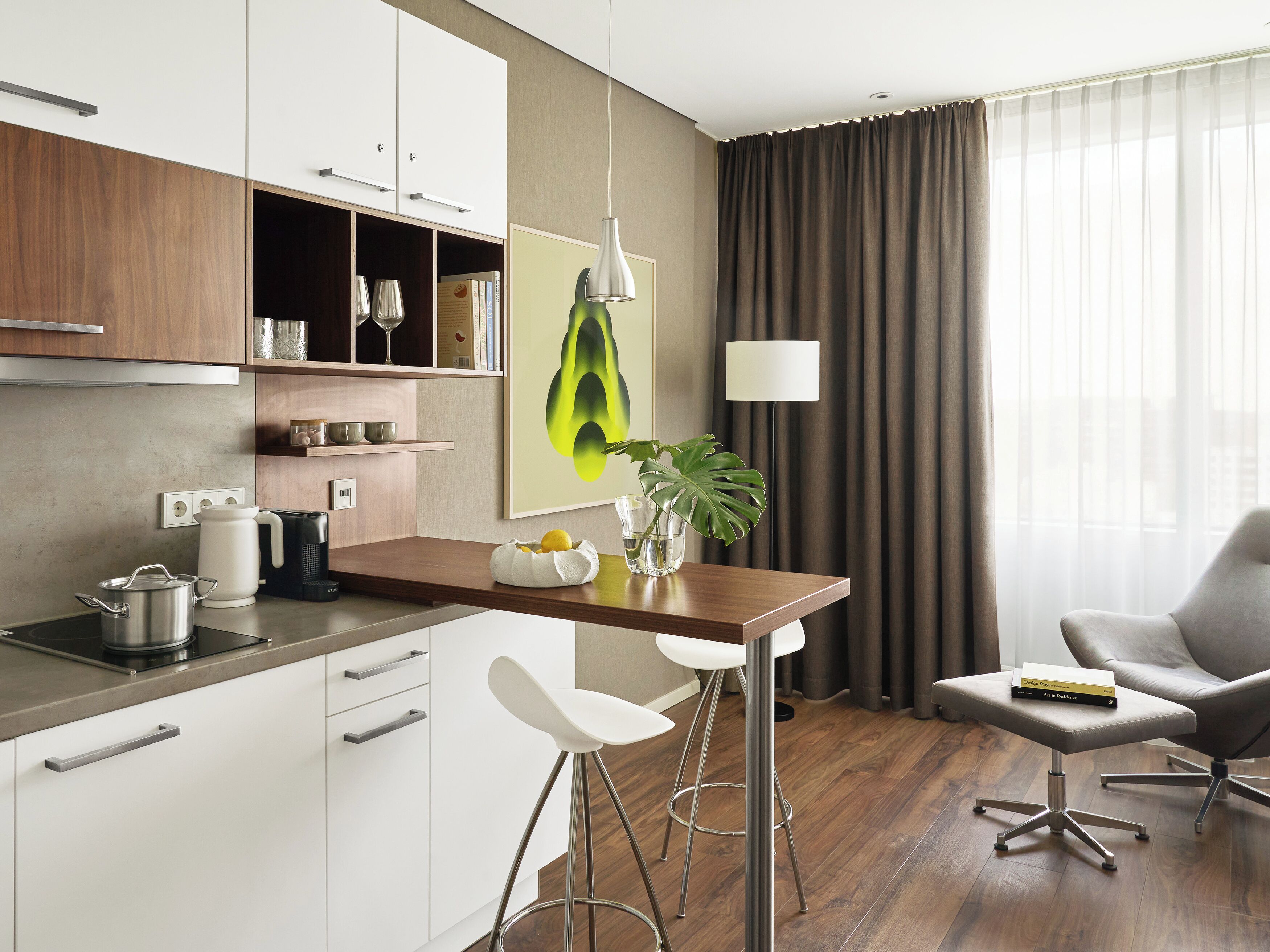 Een moderne keuken met witte kastjes, een houten aanrecht en een barkruk. Op het aanrecht staat een potplant en op de kruk ligt een boek.