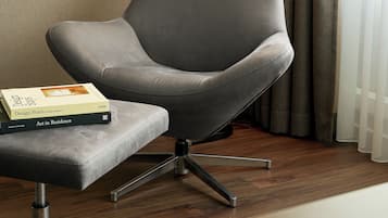 Una poltrona moderna con struttura metallica, posizionata accanto a un tavolino con un libro intitolato "Design Stays by Pete Passport".