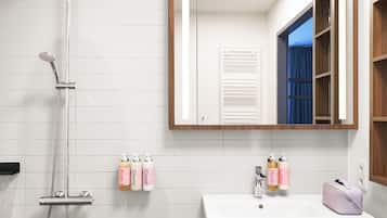 A bathroom with a shower, a sink, and a mirror. There are toiletries on the wall and a towel rack.