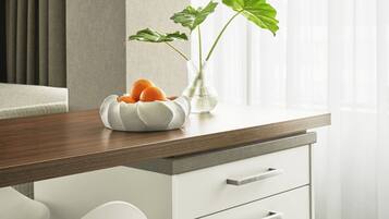 Una cocina moderna con encimera de madera, armarios blancos y un florero con hojas verdes y naranjas.