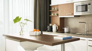 Una cocina moderna con encimera de madera, sillas blancas, microondas y cafetera.