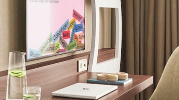 A hotel desk with a laptop, a glass of water, a lamp, and a signboard displaying various city names.