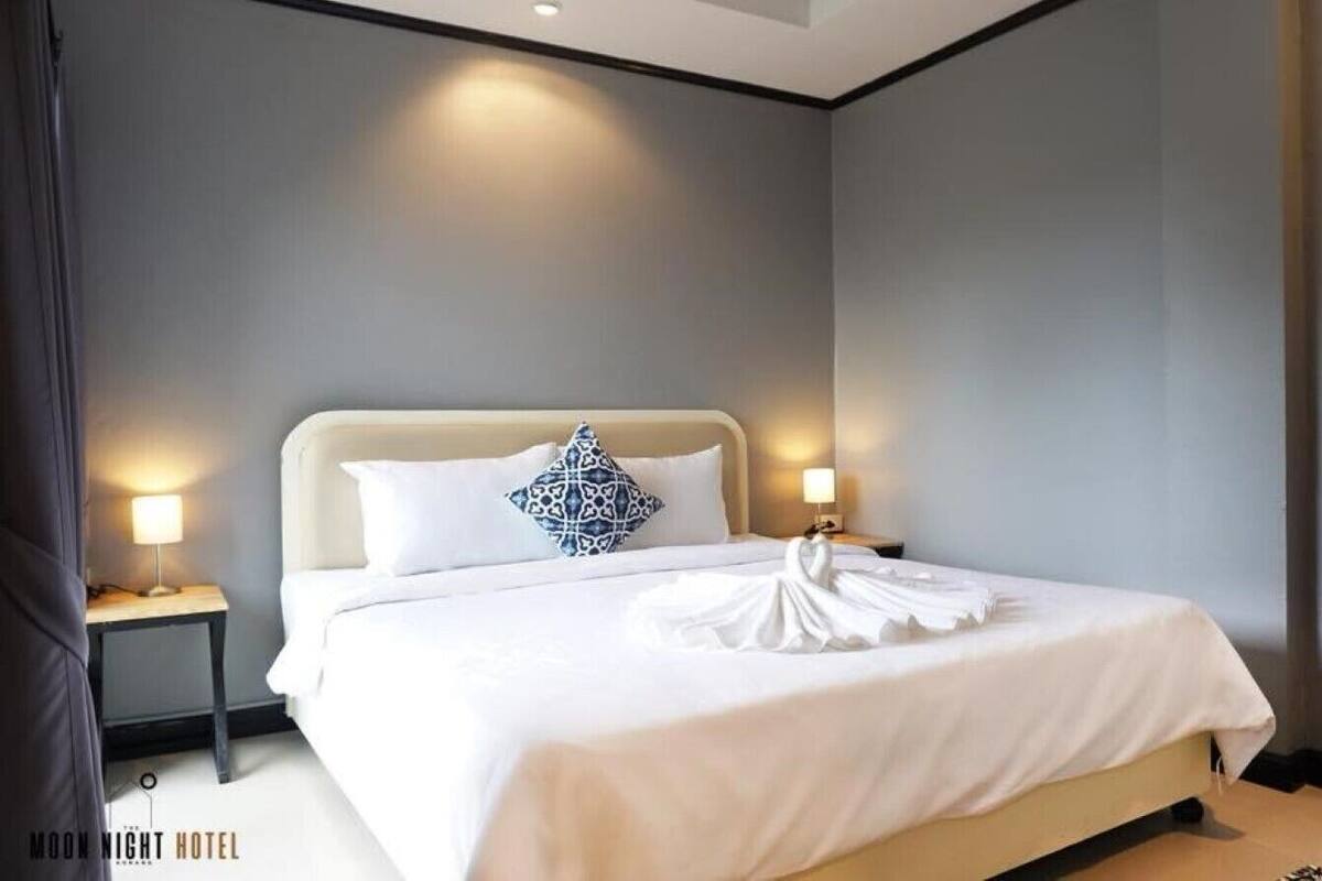 Une chambre d’hôtel avec un grand lit, deux tables de chevet avec des lampes et une tête de lit.