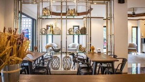 A modern dining area with a central glass partition, wooden tables, and black chairs.
