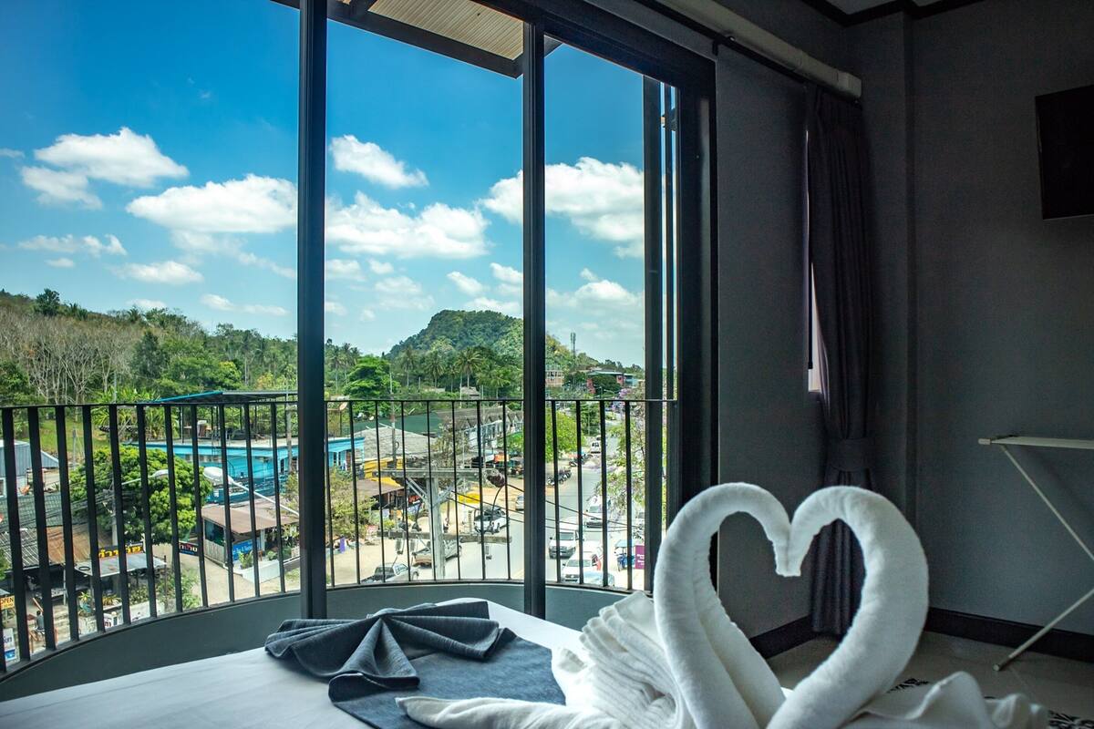 Une chambre d’hôtel dotée d’une grande fenêtre donnant sur une piscine et la végétation environnante.