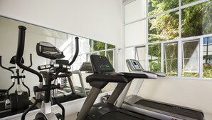 Un gimnasio con cinta de correr, elíptica y bicicleta estática.