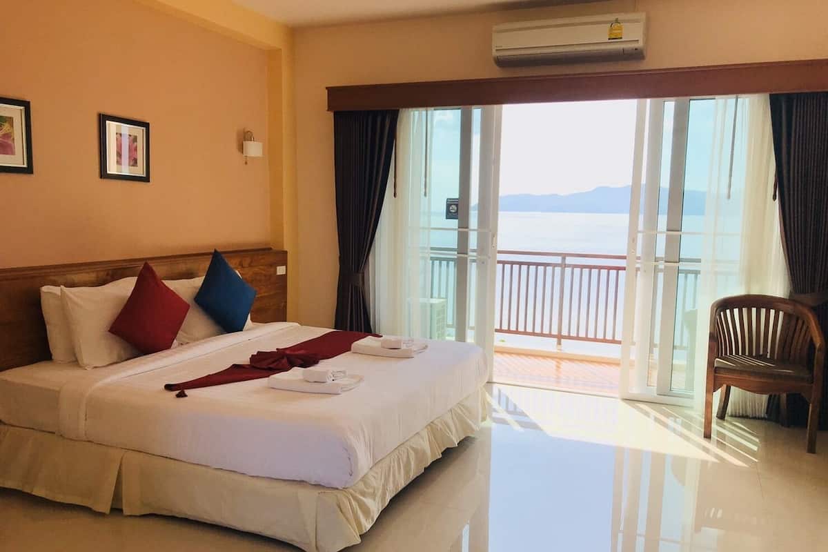 Une chambre d’hôtel avec un lit, une chaise, un balcon avec vue et un appareil de climatisation.