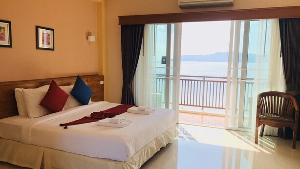 Habitación de hotel con cama, una silla, balcón con vistas y aire acondicionado.